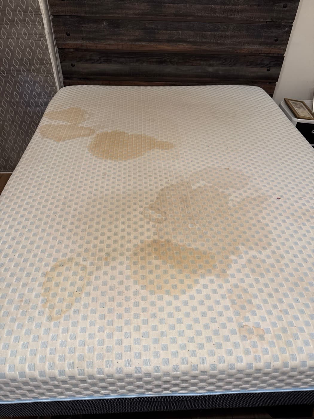 A king mattress with large yellow stains, before cleaning