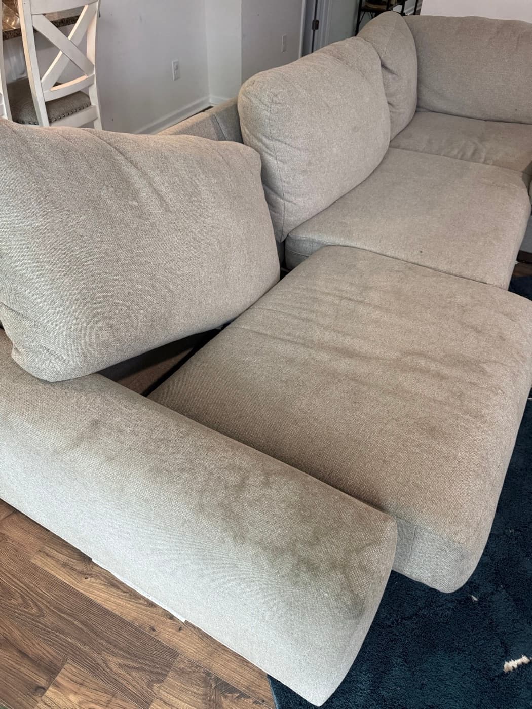 A beige three-seat sofa with soiled seat cushions, before cleaning