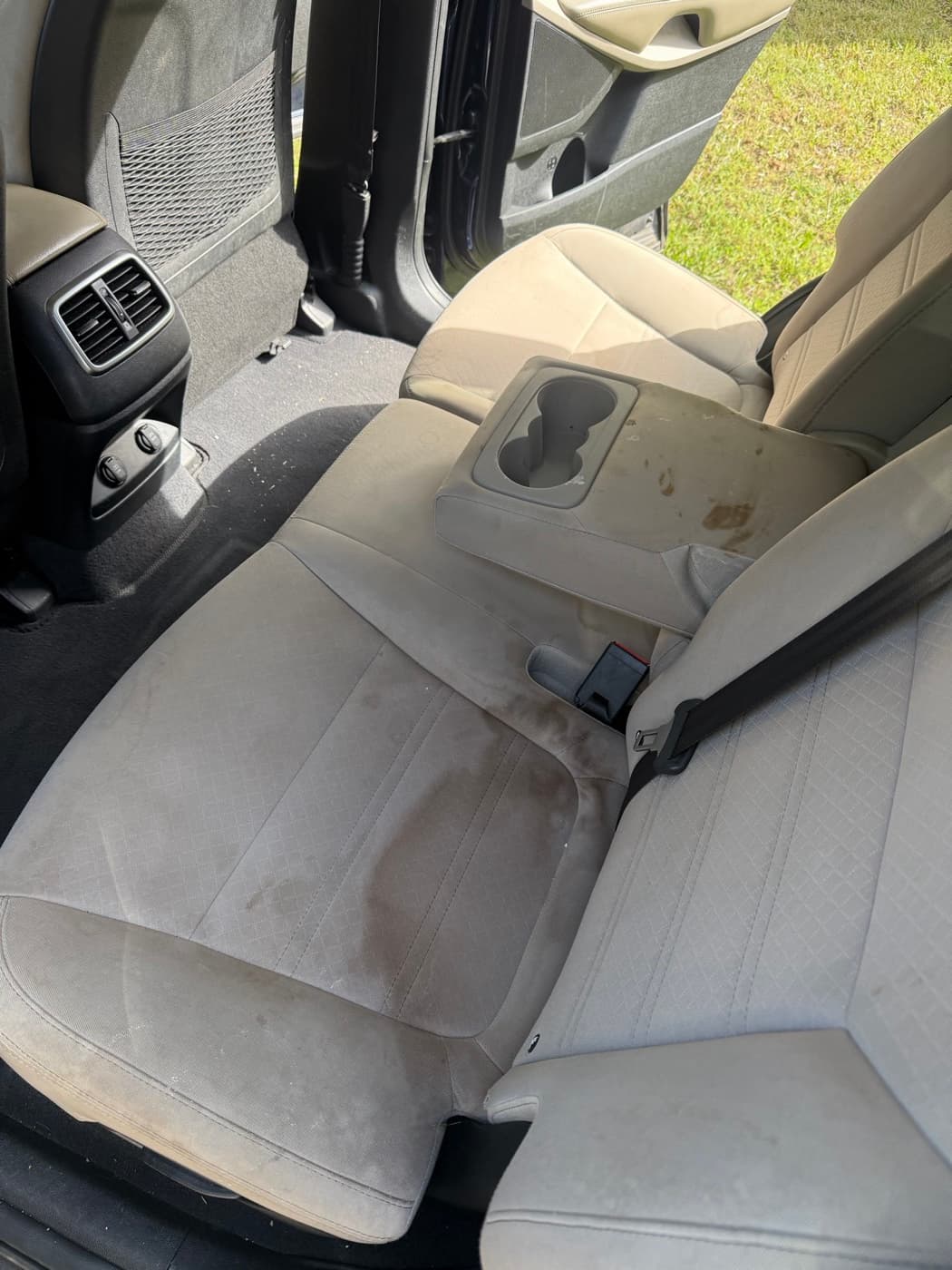 A cream rear seat in a car with marks across the base, before cleaning