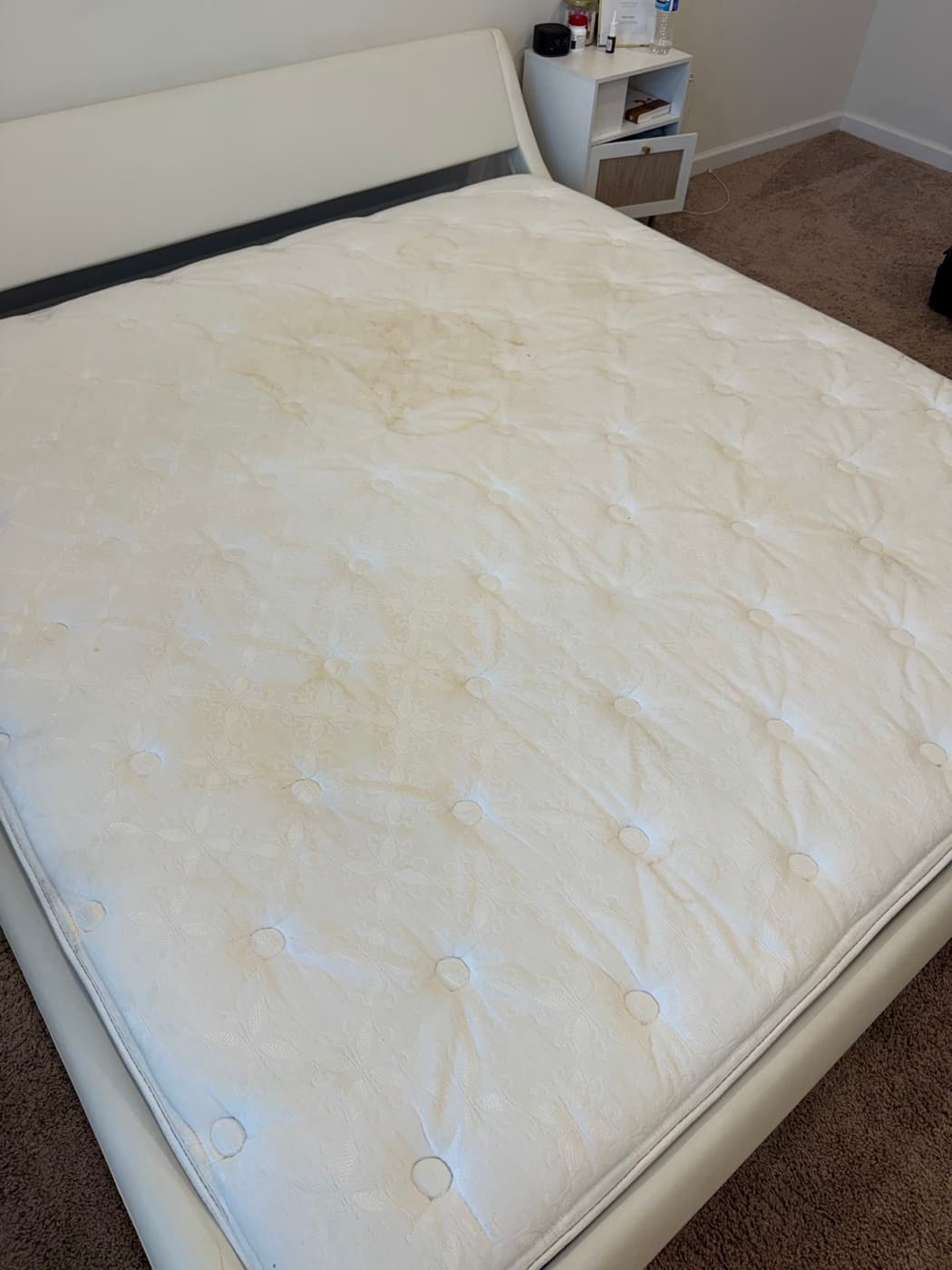 A double mattress with large yellow stains, before cleaning