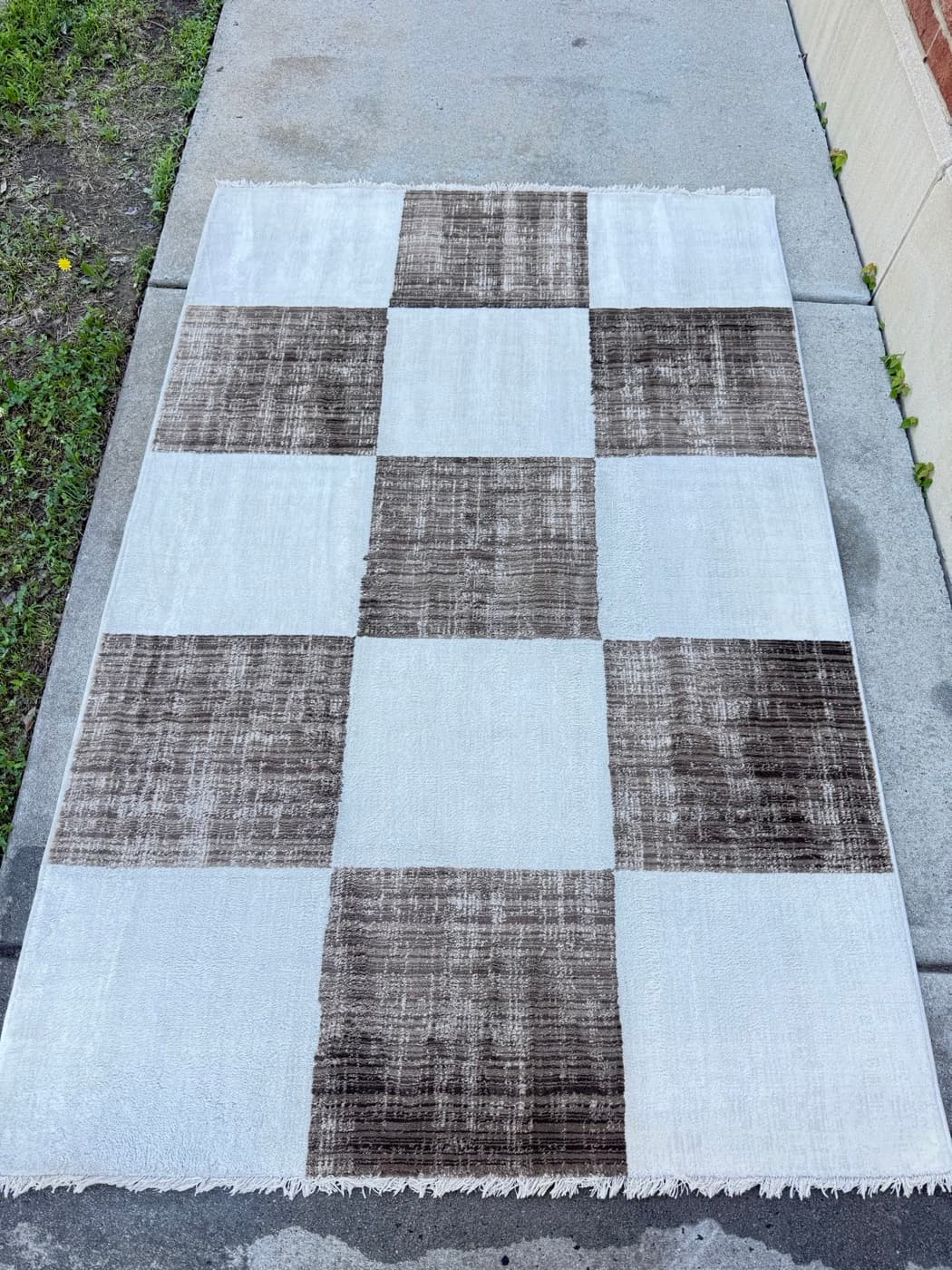 The same black and white checked flatweave rug after steam cleaning
