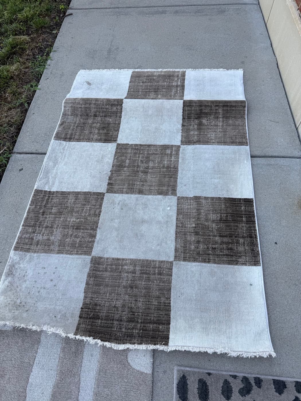 A black and white checked flatweave rug, before cleaning