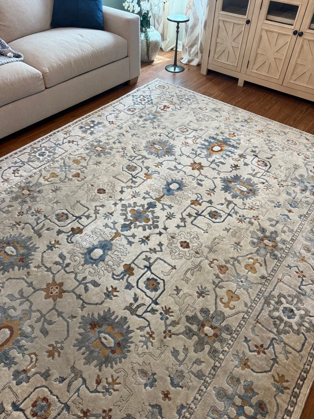 A patterned cream and blue wool area rug dulled by foot traffic, before cleaning