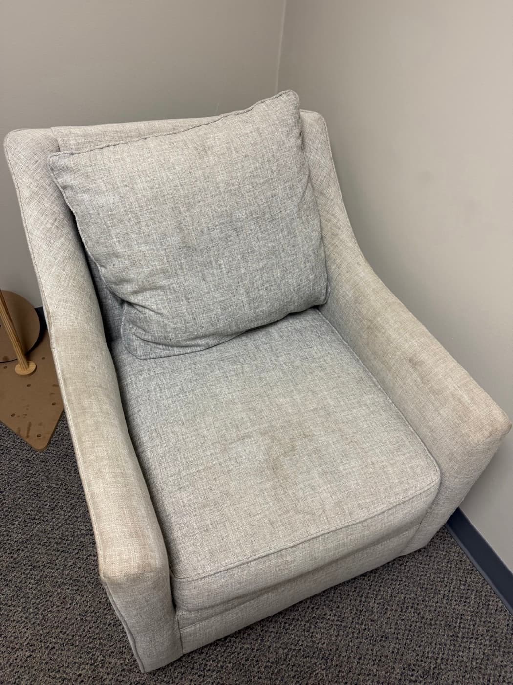 A cream armchair with a loose seat cushion, before cleaning