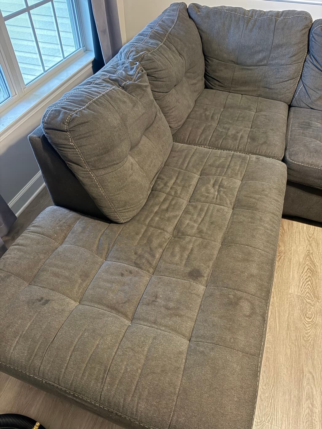 A beige tufted sofa bed, before cleaning