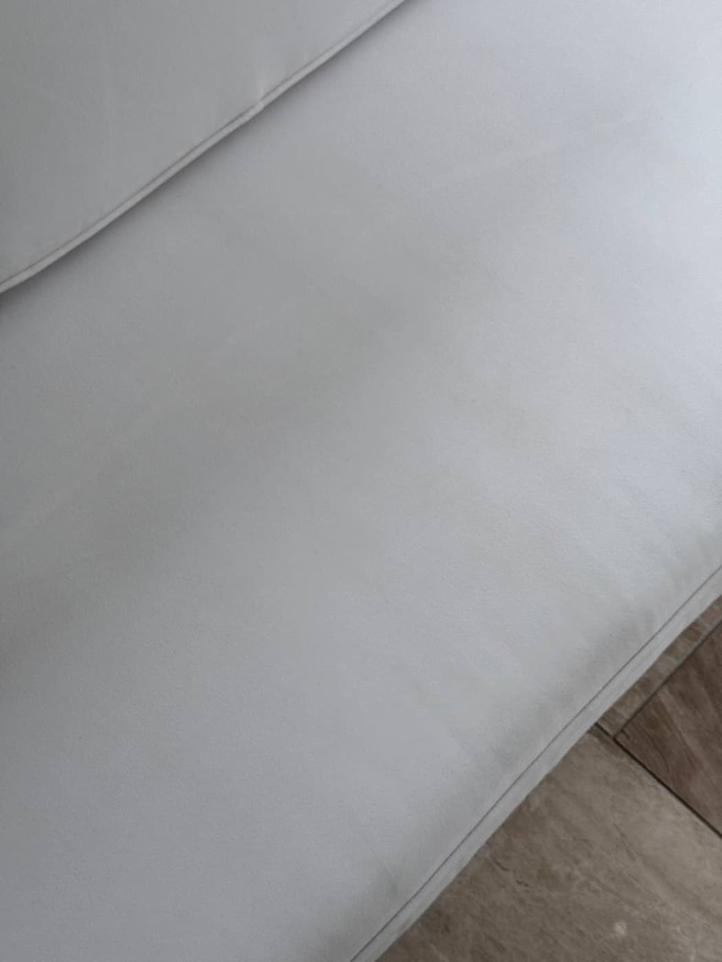 The same white sofa arm and seat edge after steam cleaning
