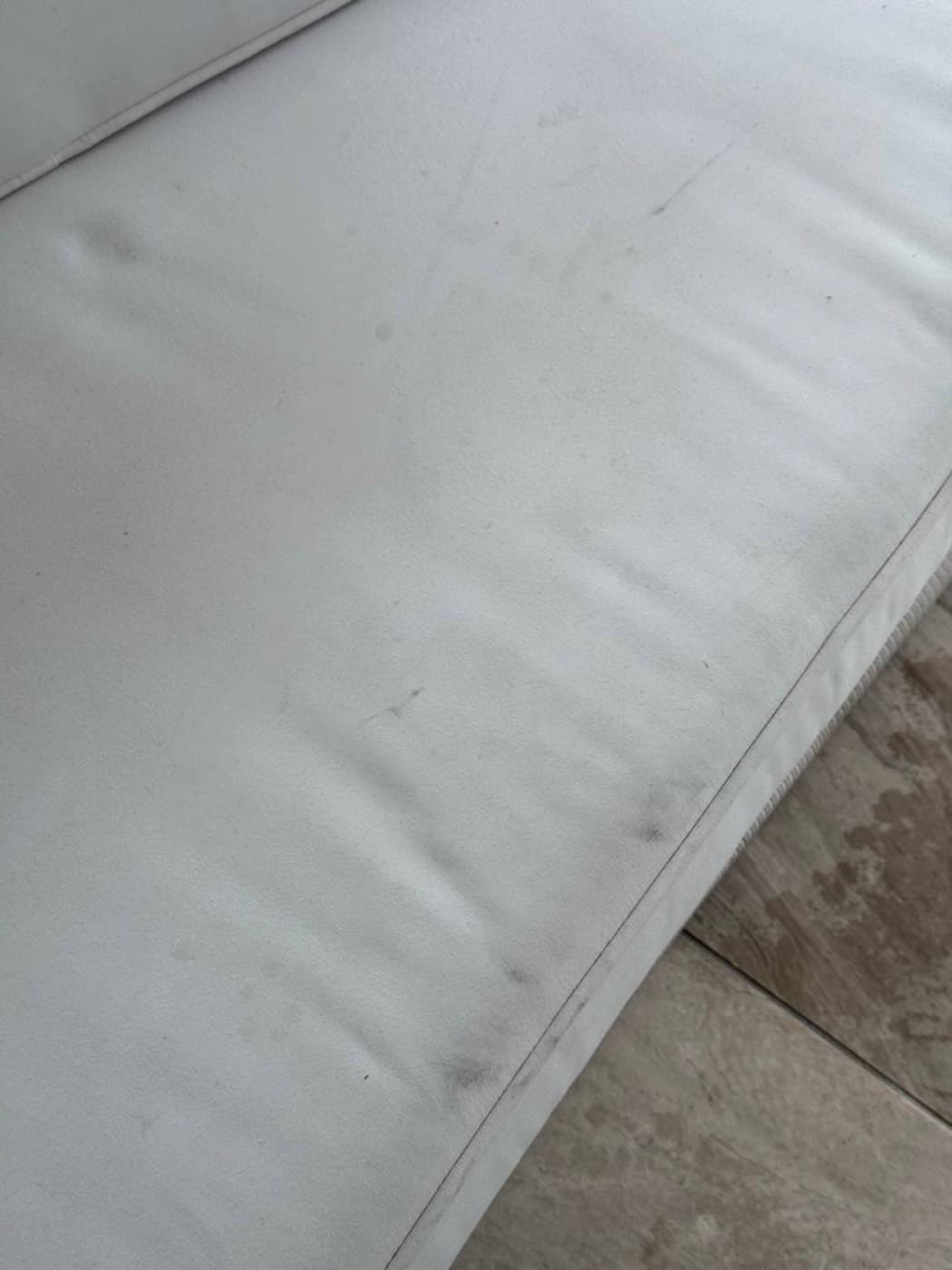 A white sofa arm and seat edge with grey marks, before cleaning