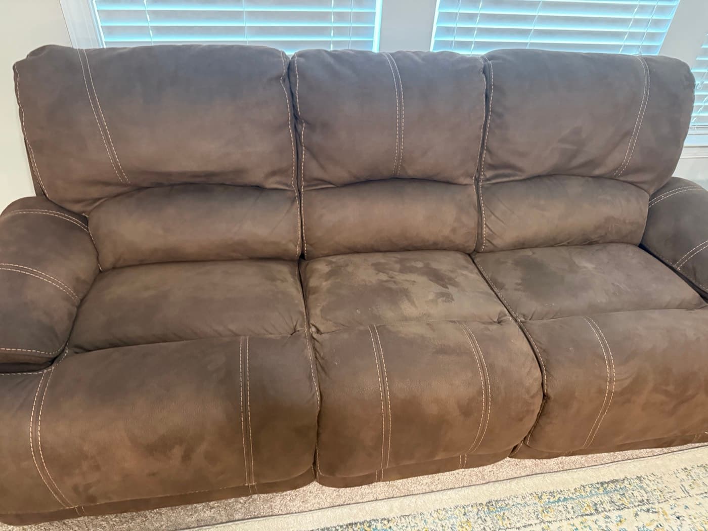 A taupe three-seat reclining sofa, heavily soiled, before cleaning
