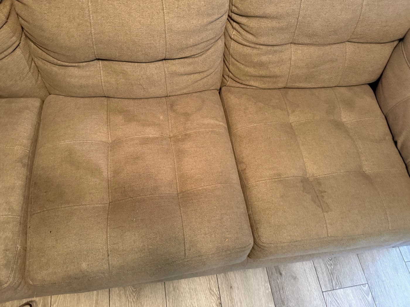 A taupe three-seat sofa with soiled seat cushions, before cleaning